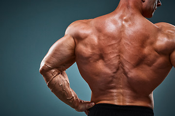 Image showing torso of attractive male body builder on gray background.