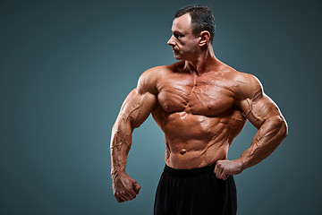 Image showing torso of attractive male body builder on gray background.