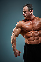 Image showing torso of attractive male body builder on gray background.