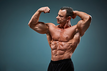 Image showing torso of attractive male body builder on gray background.