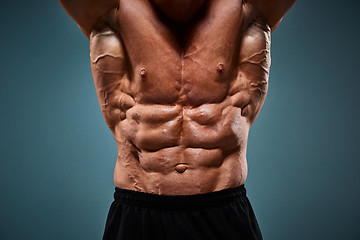 Image showing torso of attractive male body builder on gray background.