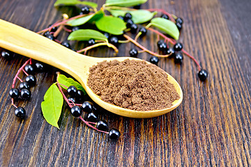 Image showing Flour bird cherry in spoon with berries on dark board