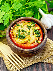 Image showing Fish baked with tomato in clay bowl on dark board