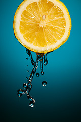 Image showing Lemon slice and splash of juice isolated on blue background