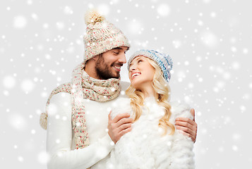 Image showing smiling couple in winter clothes hugging over snow