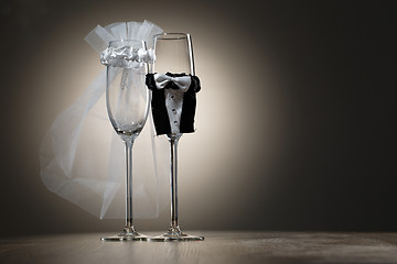 Image showing Elegant champagne glasses dressed in mini suitsof bride and groom