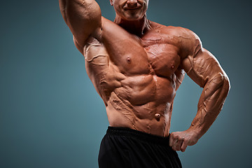 Image showing torso of attractive male body builder on gray background.