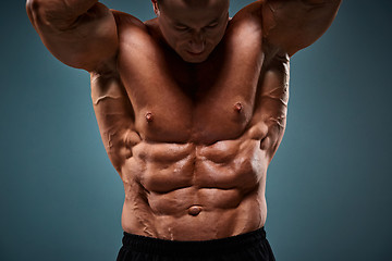 Image showing torso of attractive male body builder on gray background.