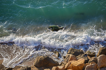 Image showing Clear turquoise sea washes yellow stones on sunny summer day