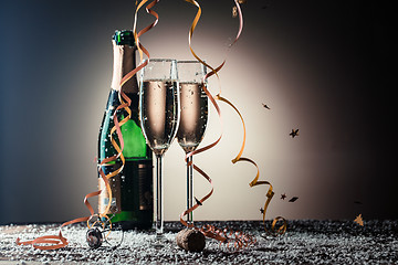 Image showing Bottle of champagne, wineglasses with golden ribbons, snowflakes and serpentine