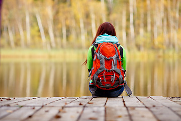 Image showing Girls sitting back on bridge in autumn forest