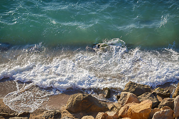 Image showing Transparent waves crash on rocky shore