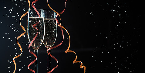 Image showing Two glasses with champagne, decorative ribbons and snowflakes closeup