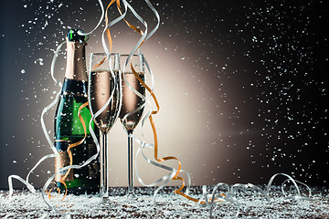 Image showing Bottle, two champagne wineglasses with silver and golden ribbons, snowfall