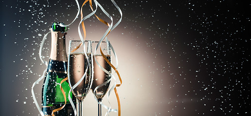 Image showing Green bottle of champagne, wineglasses with silver and golden ribbons