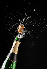 Image showing Cork flies out of champagne bottle isolated on black background