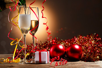 Image showing Champagne pouring from bottle into glasses and Christmas decorations