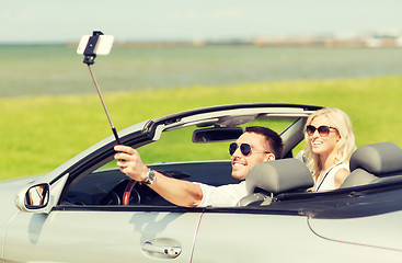 Image showing happy couple in car taking selfie with smartphone