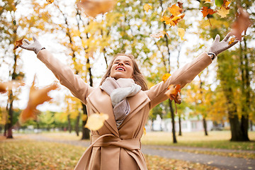 Image showing happy woman having fun with leaves in autumn park