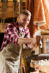 Image showing carpenter working with plane and wood at workshop