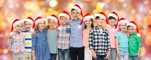 Image showing happy smiling children in santa hats hugging