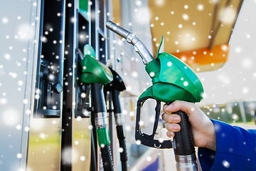 Image showing close up of hand holding hose at gas station