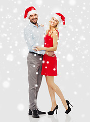 Image showing happy couple in santa hats hugging over snow
