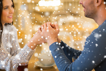 Image showing happy couple with tea holding hands at restaurant