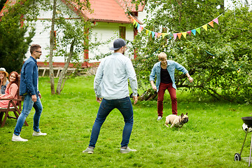 Image showing happy friends playing with dog at summer garden