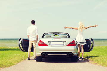 Image showing happy man and woman near cabriolet car at sea