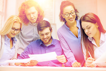 Image showing smiling team with paper at office