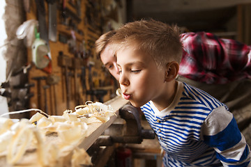 Image showing father and little son with wood plank at workshop