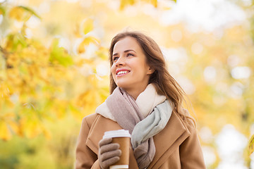 Image showing happy young woman drinking coffee in autumn park