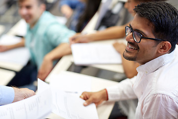 Image showing happy student with exam test or handout at lecture