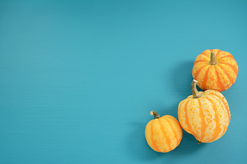 Image showing Three yellow and orange Festival squash on blue wooden backgroun