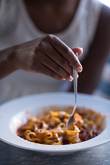 Image showing a young African American woman eating pasta