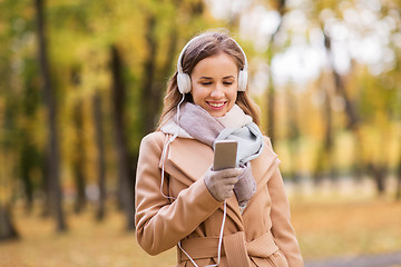 Image showing woman with smartphone and earphones in autumn park