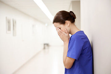 Image showing sad or crying female nurse at hospital corridor