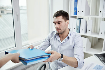 Image showing businessman taking folder from secretary in office