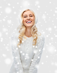 Image showing smiling young woman in winter earmuffs and sweater