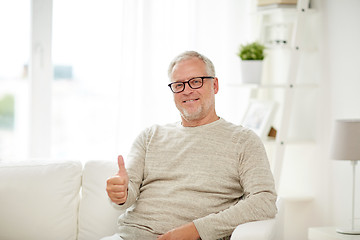 Image showing smiling senior man showing thumbs up at home
