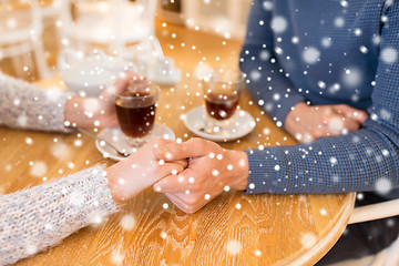 Image showing close up of couple holding hands at restaurant