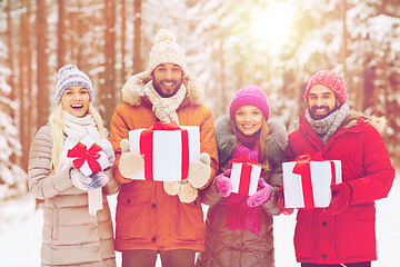 Image showing happy friends with gift boxes in winter forest