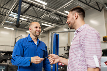 Image showing auto mechanic giving key to man at car shop