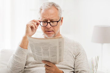 Image showing senior man in glasses reading newspaper at home