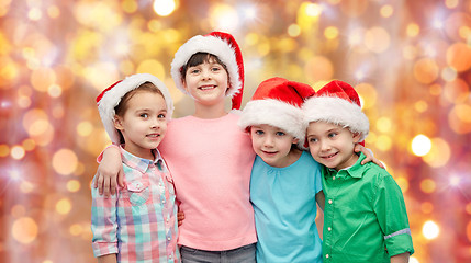 Image showing happy little children in santa hats hugging