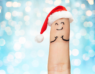 Image showing close up of one finger in santa hat over lights