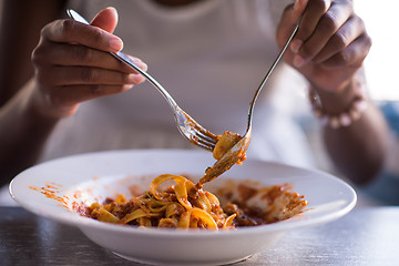 Image showing a young African American woman eating pasta