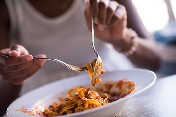 Image showing a young African American woman eating pasta