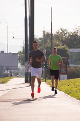 Image showing Two young men jogging through the city